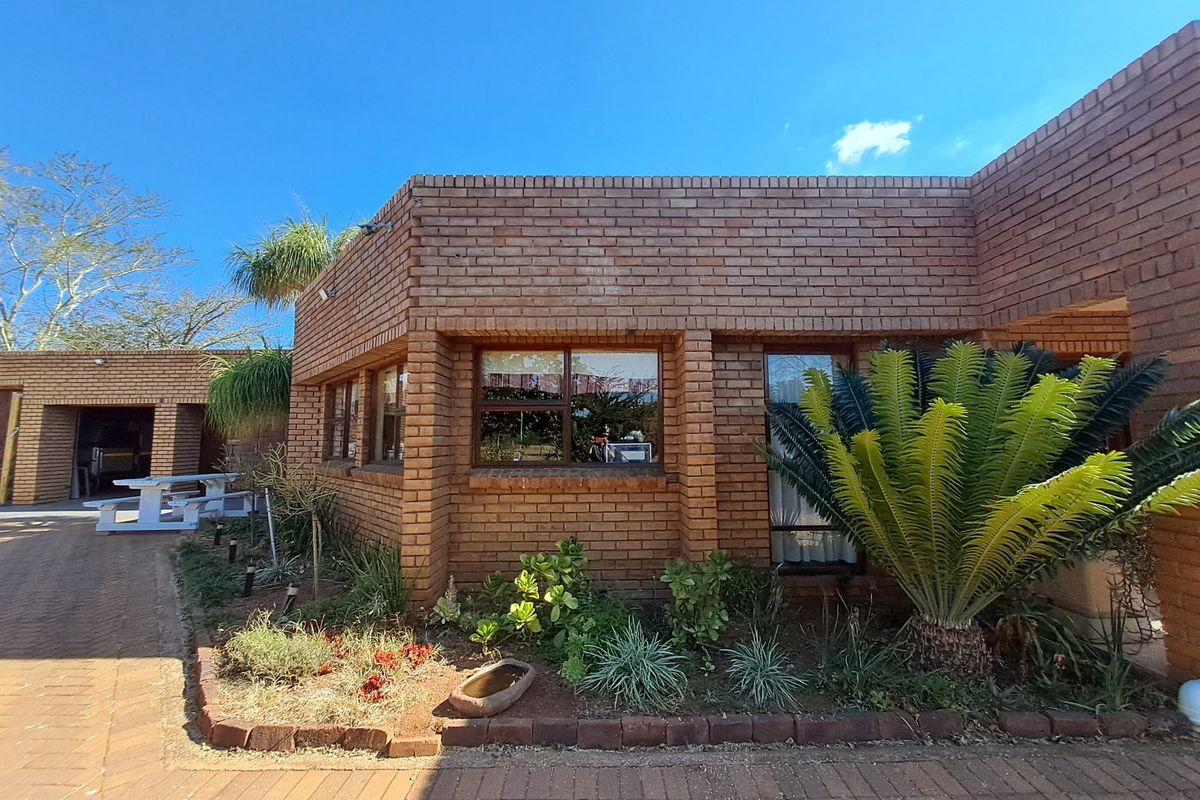 A well-maintained face brick exterior featuring paved pathways and established garden landscaping, showcasing the property's durable construction and outdoor access.