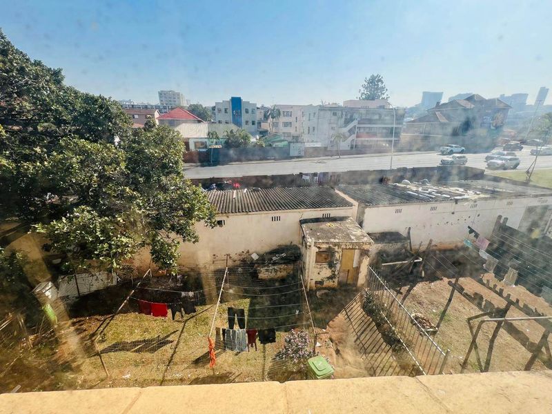 An elevated view overlooking a residential backyard area with perimeter walls, fencing, and surrounding urban neighborhood buildings.