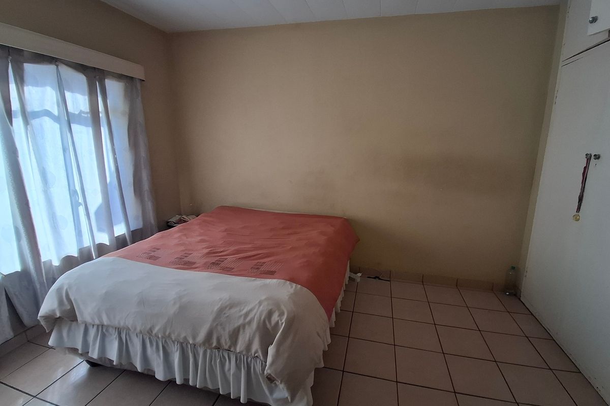 A bedroom featuring tiled flooring and a built-in wardrobe, requiring cosmetic updates to the wall finishes.