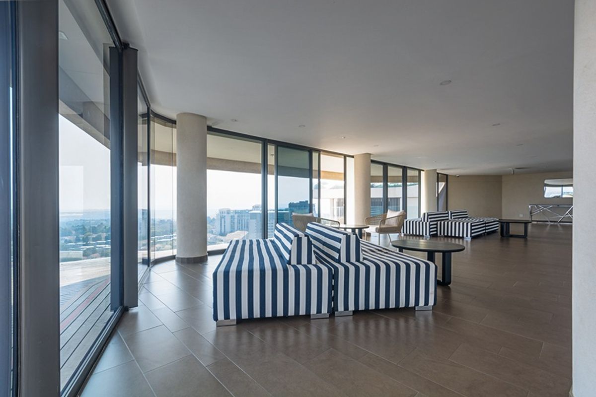 Spacious living area featuring floor-to-ceiling glass sliding doors that provide expansive views and abundant natural light, complemented by modern tiled flooring.