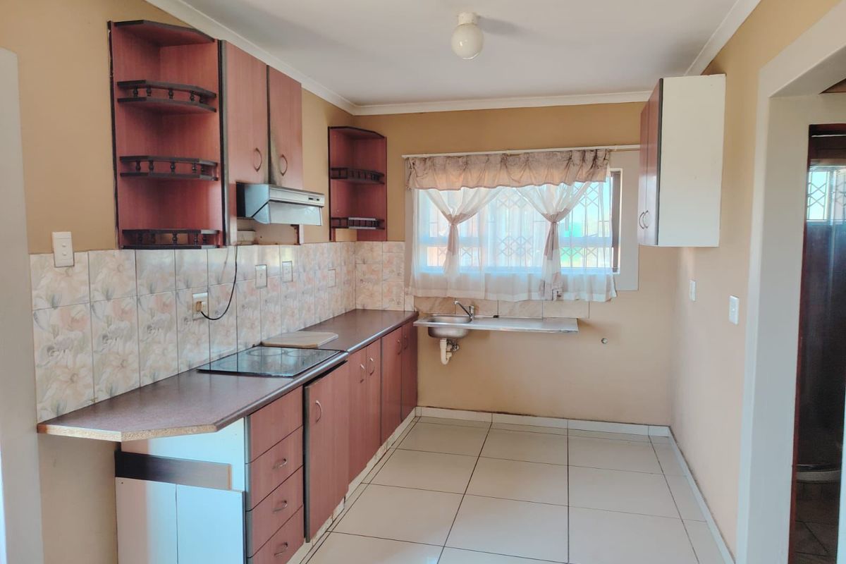 A functional kitchen featuring laminate countertops, built-in cabinetry, a ceramic tile backsplash, and tiled flooring, offering a clean and practical workspace.