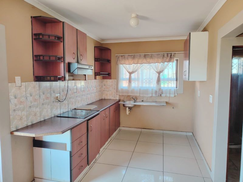 A functional kitchen featuring laminate countertops, built-in cabinetry, a ceramic tile backsplash, and tiled flooring, offering a clean and practical workspace.