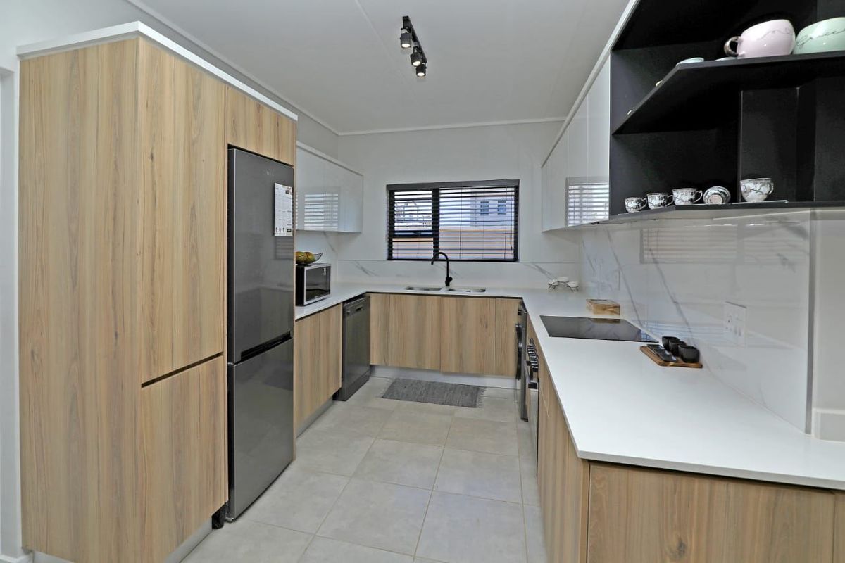 Modern kitchen featuring wood-grain and white cabinetry, stone countertops, integrated appliances, and sleek finishes with ample storage and workspace.