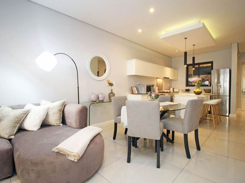 Modern open-plan living and dining area featuring tiled floors, recessed lighting, and a functional kitchen with built-in cabinetry and island.