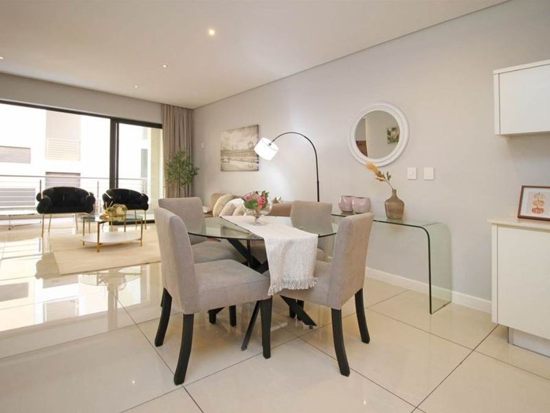 Modern open-plan living and dining area featuring polished tiled floors, recessed lighting, and seamless access to a private balcony.
