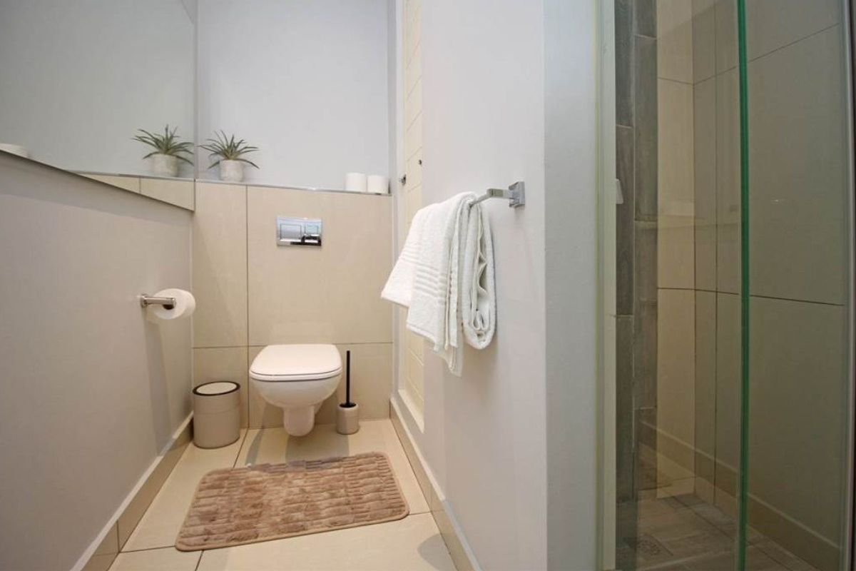 Modern bathroom featuring a wall-hung toilet with concealed cistern, glass shower enclosure, and neutral tiled finishes.