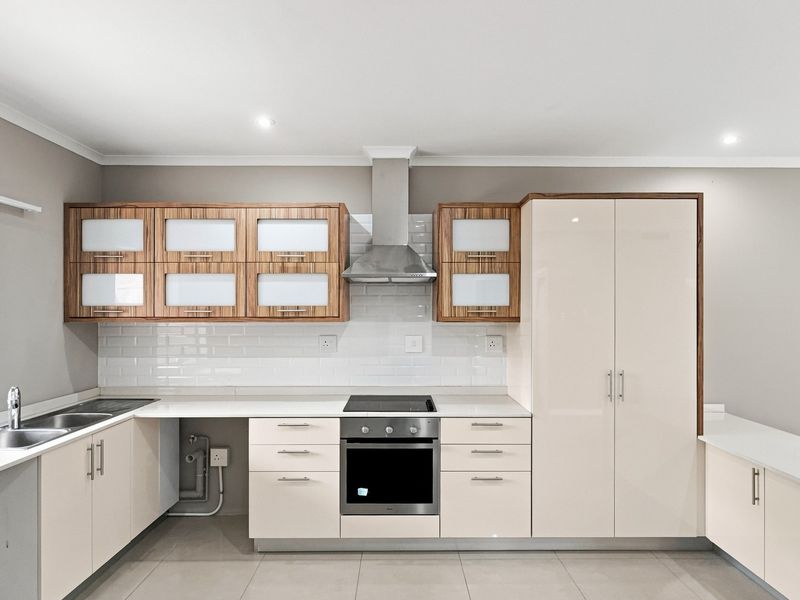 Modern kitchen featuring sleek cabinetry, stone countertops, subway tile backsplash, and integrated stainless steel appliances including an oven and extractor fan.
