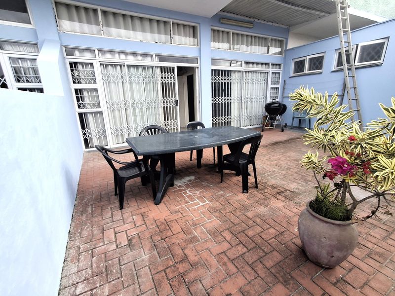 A paved outdoor patio area featuring security gates and sliding door access to the interior, providing a functional space for outdoor living.