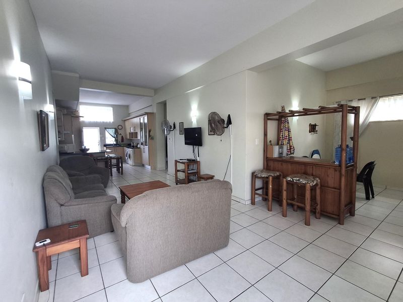 Spacious open-plan living area featuring tiled flooring, a functional kitchen with built-in cabinetry, and a dedicated breakfast bar area.