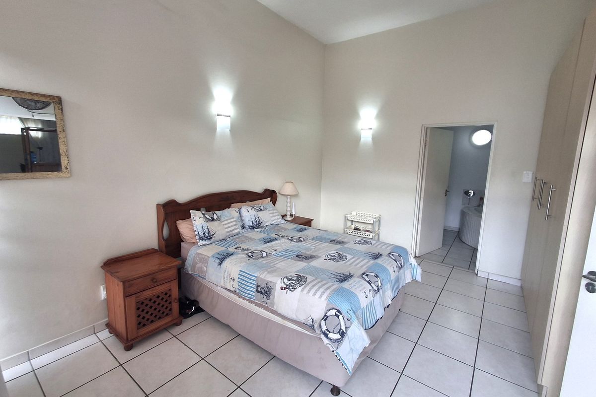 Spacious bedroom featuring tiled flooring, built-in cupboards, and direct access to an en-suite bathroom with neutral wall finishes.