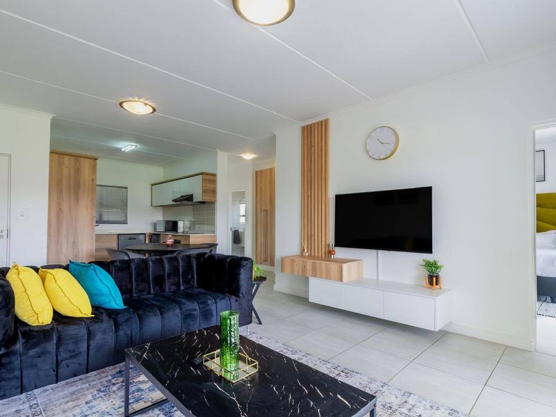Modern open-plan living area featuring tiled floors, contemporary timber wall accents, and a seamless transition into the kitchen space.