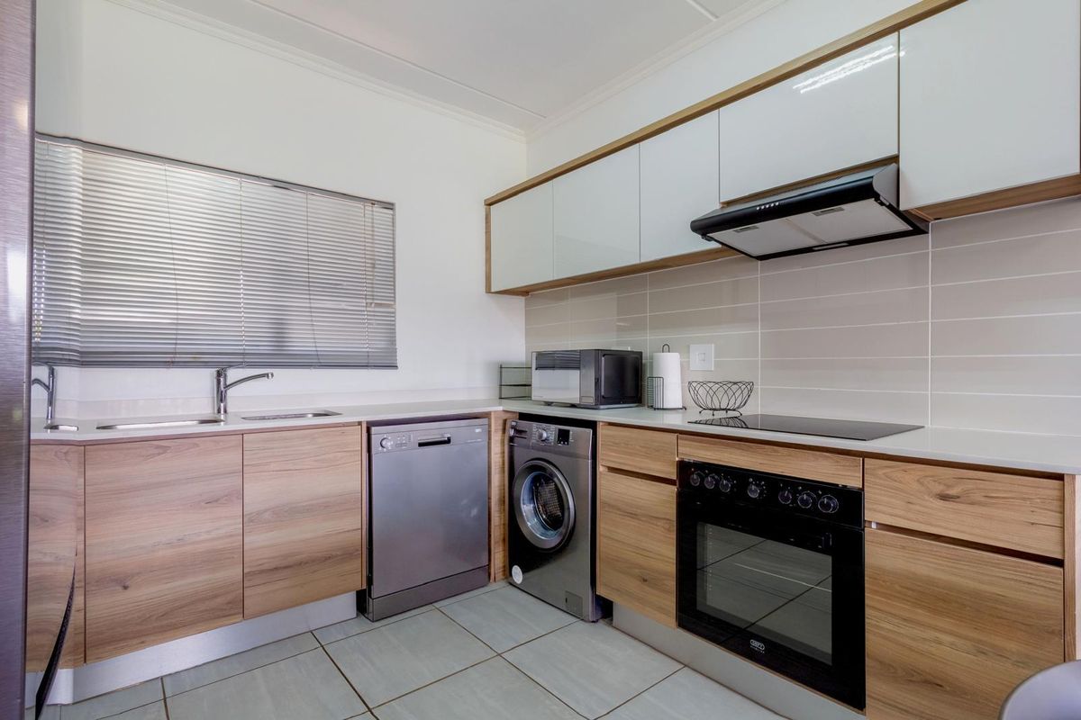 Modern kitchen featuring wood-finish cabinetry, integrated appliances, sleek tiled backsplash, and a functional layout with ample counter space.