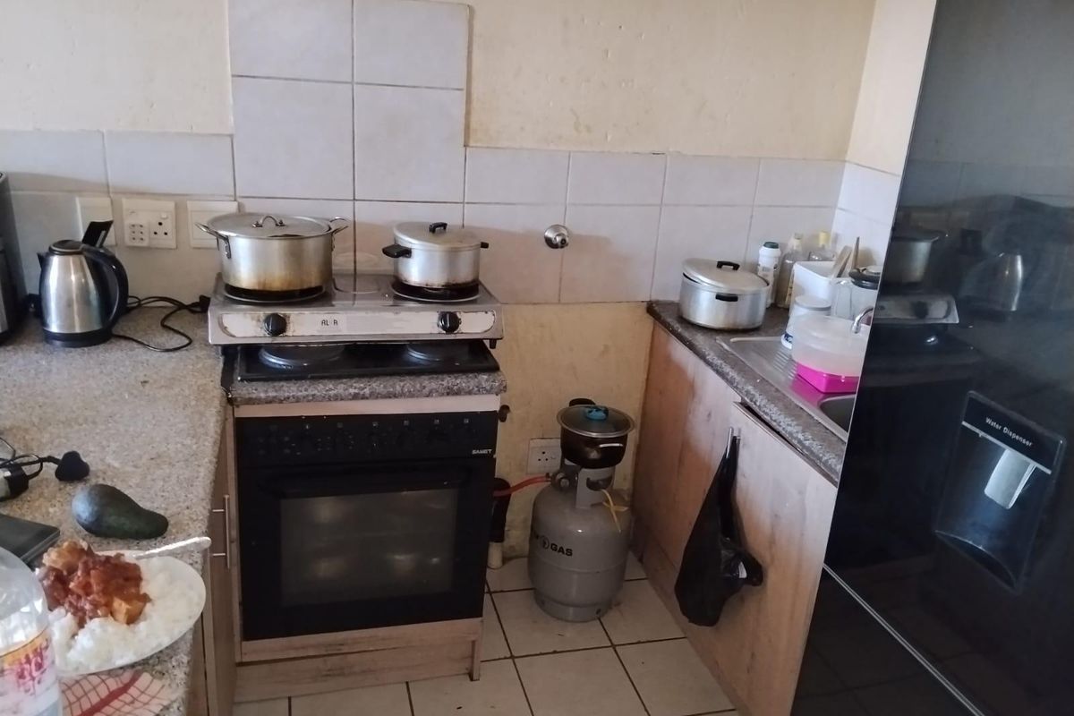 Compact kitchen featuring granite countertops, built-in oven, gas hob, and tiled backsplash. The space requires cosmetic updates to improve its overall condition.
