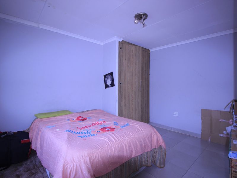 A bedroom featuring tiled flooring and a built-in wooden wardrobe, requiring minor cosmetic updates to the wall finishes.