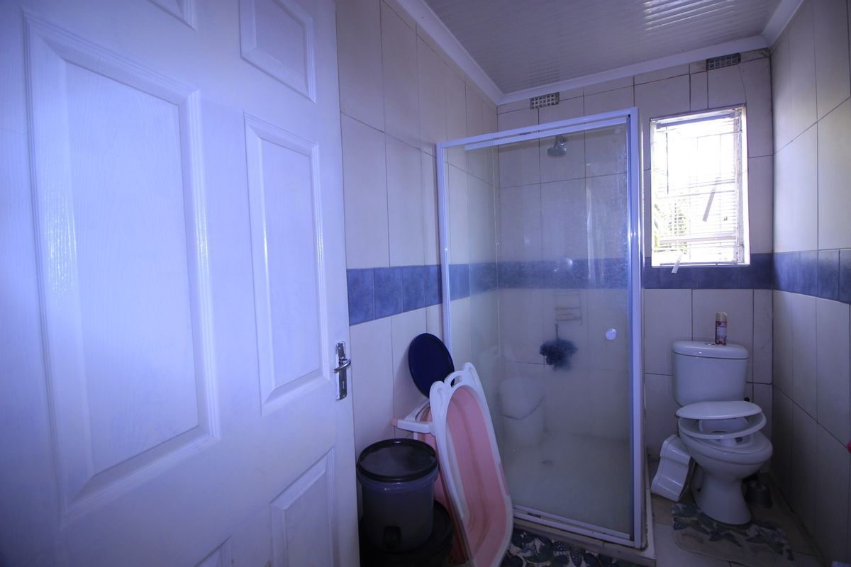 A functional bathroom featuring a shower enclosure, toilet, and tiled wall finishes.