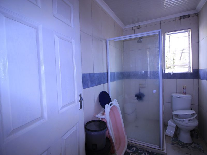 A functional bathroom featuring a shower enclosure, toilet, and tiled wall finishes.