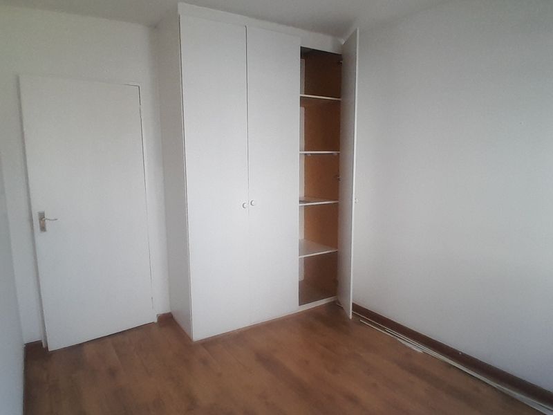 An empty bedroom featuring laminate flooring and a built-in wardrobe with shelving.