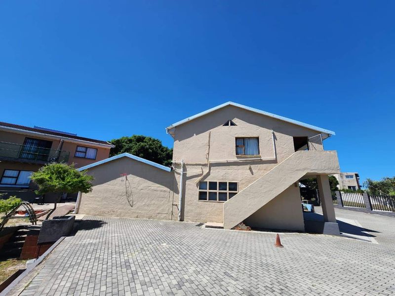 Exterior view of a two-story residential building featuring a paved driveway, external staircase, and neutral rendered facade.