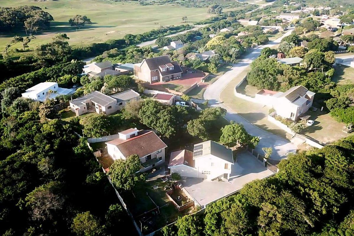An aerial view of a residential neighborhood featuring multiple houses with tiled roofs, paved driveways, and surrounding greenery.