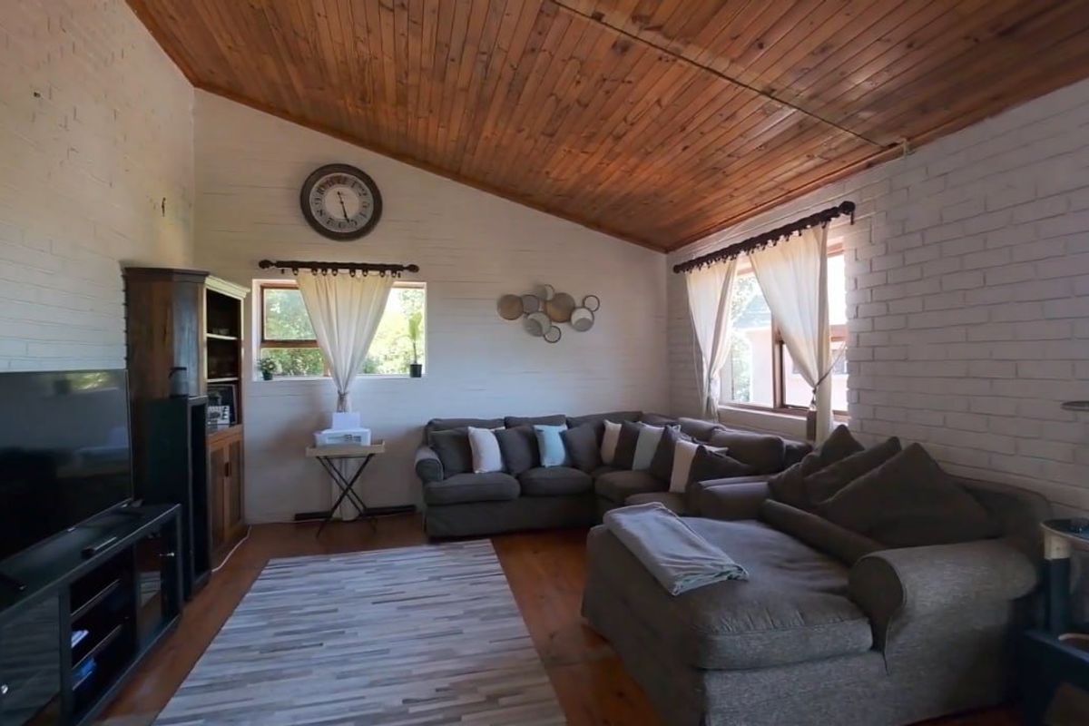 A cozy living room featuring a raked timber ceiling, painted brick walls, and warm timber flooring, creating a rustic and inviting atmosphere.