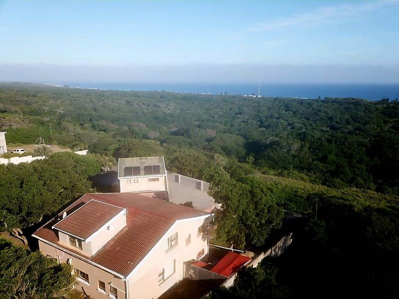 Aerial view of the property showcasing the roof structure, solar panels, and surrounding coastal landscape.