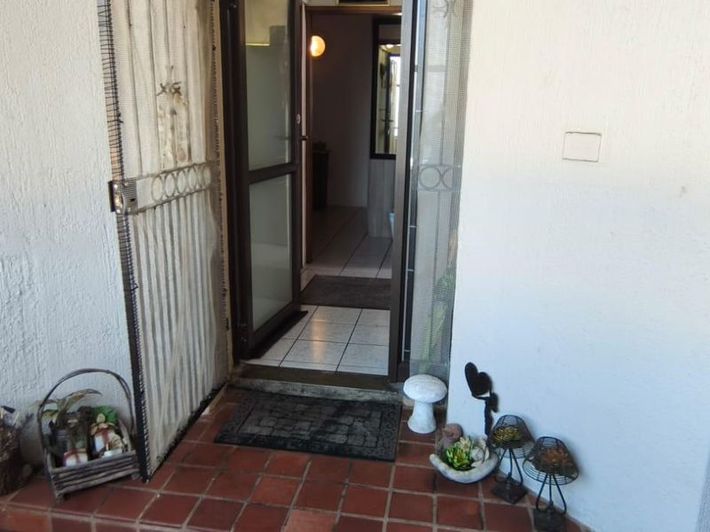 Entrance area featuring a security gate, tiled flooring, and a handrail leading into the apartment interior.