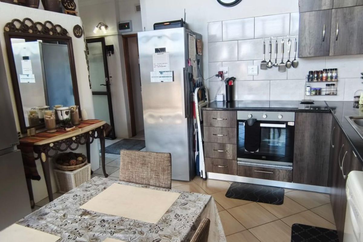 A functional kitchen featuring dark wood-finish cabinetry, a built-in oven and hob, tiled backsplash, and a double basin sink with tiled flooring.