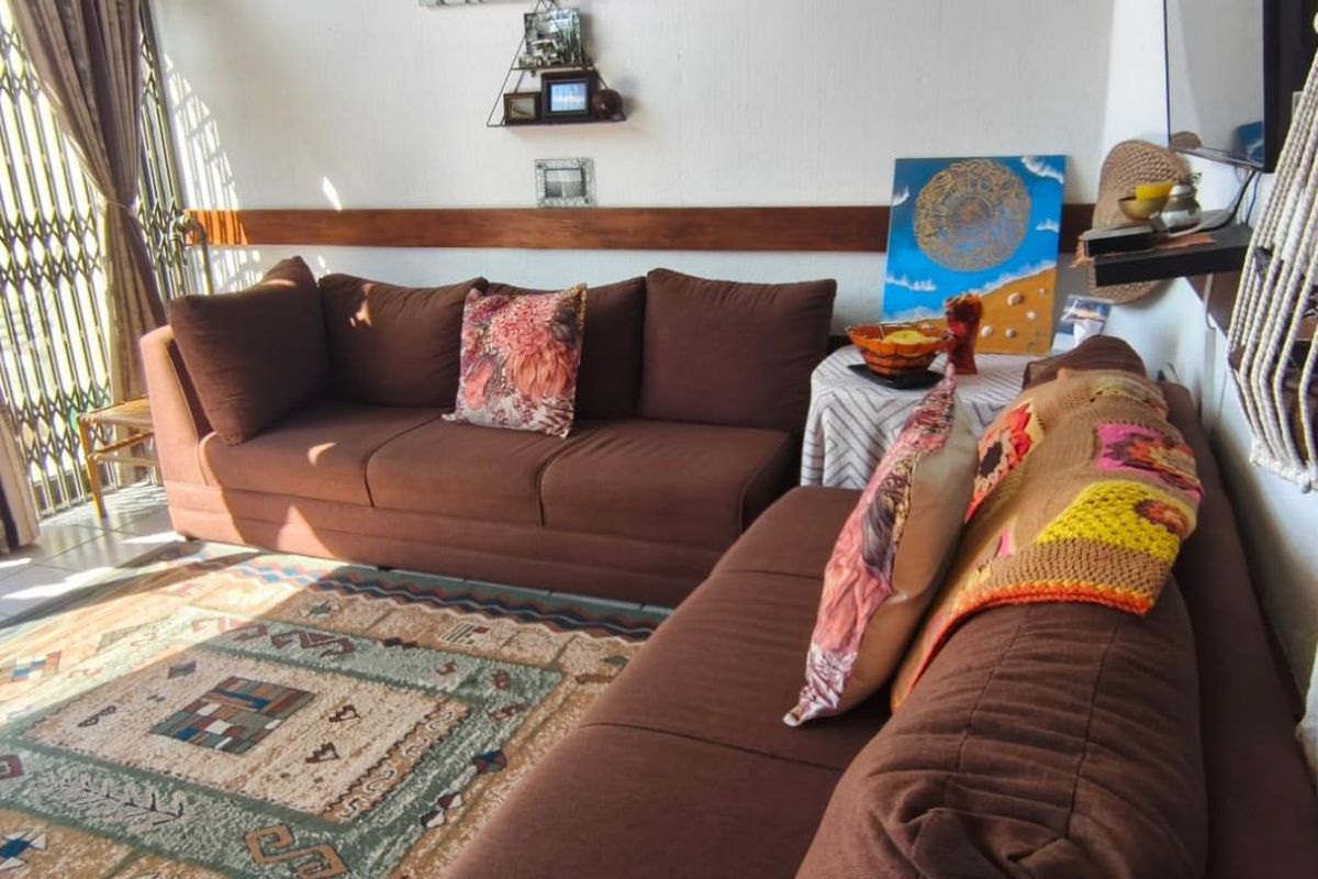 A living room featuring tiled flooring, a wooden dado rail, and a sliding door leading to an outdoor area with a security gate.