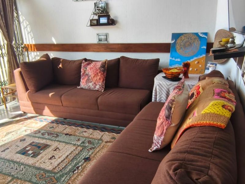 A living room featuring tiled flooring, a wooden dado rail, and a sliding door leading to an outdoor area with a security gate.