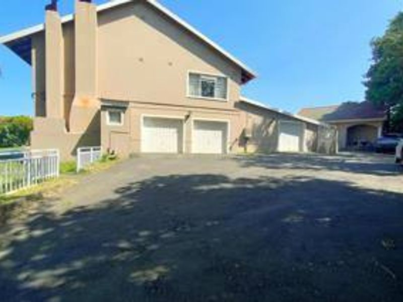 Front exterior view of a multi-level house featuring a triple garage, asphalt driveway, and external chimney stack.