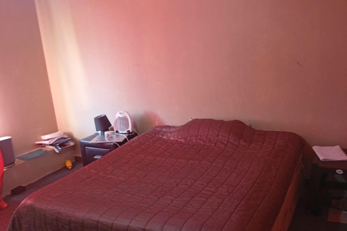 A bedroom featuring a simple layout with carpeted flooring and a standard ceiling finish, offering a blank canvas for potential updates.