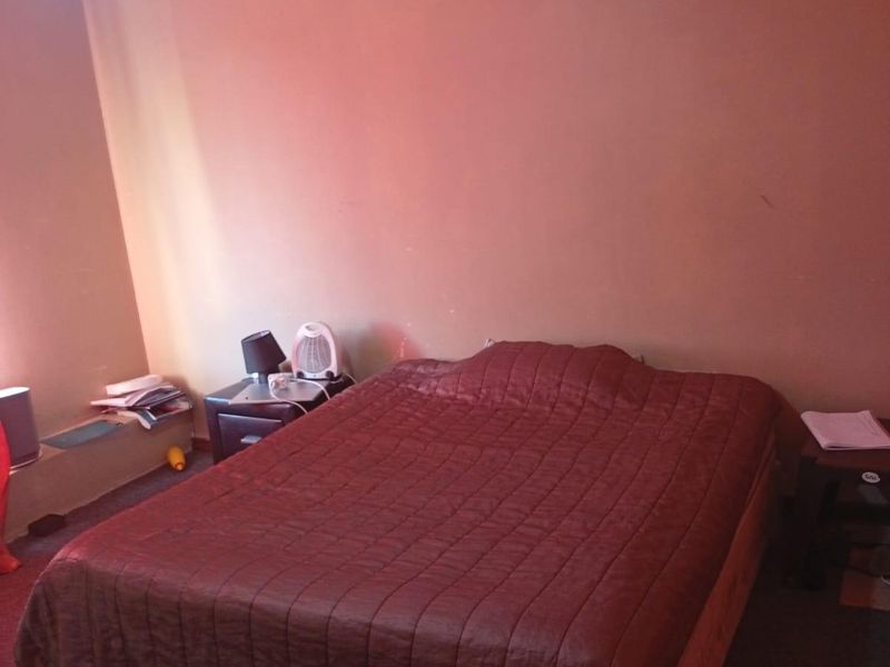 A bedroom featuring a simple layout with carpeted flooring and a standard ceiling finish, offering a blank canvas for potential updates.