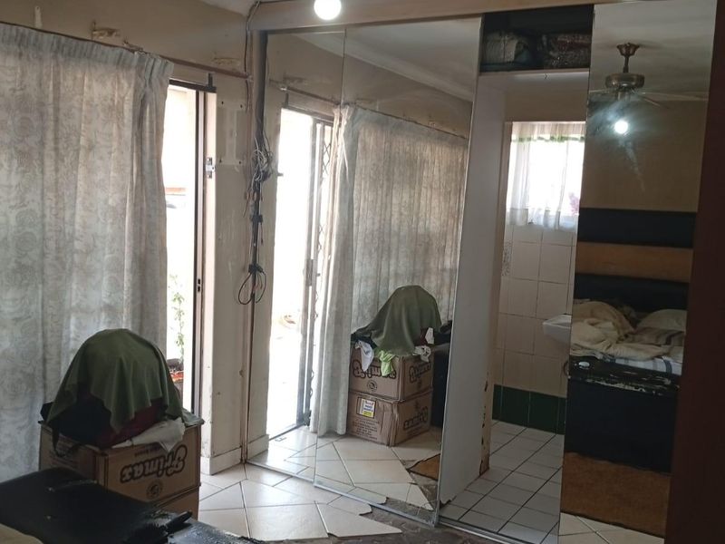 Bedroom featuring mirrored sliding wardrobes, tiled flooring, and a ceiling fan, with direct access to an outdoor area via a sliding glass door.