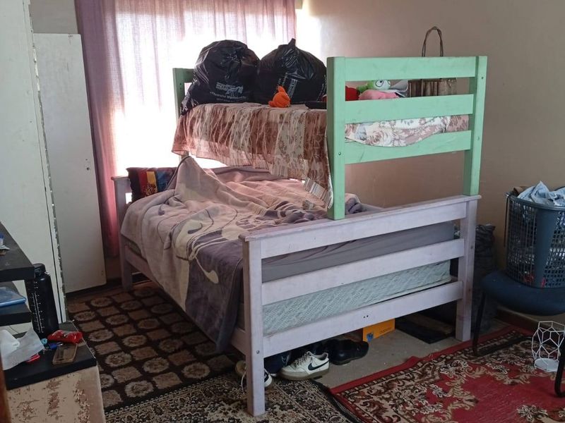 A bedroom featuring visible ceiling water damage and worn wall finishes, requiring maintenance and cosmetic updates to improve the overall condition.