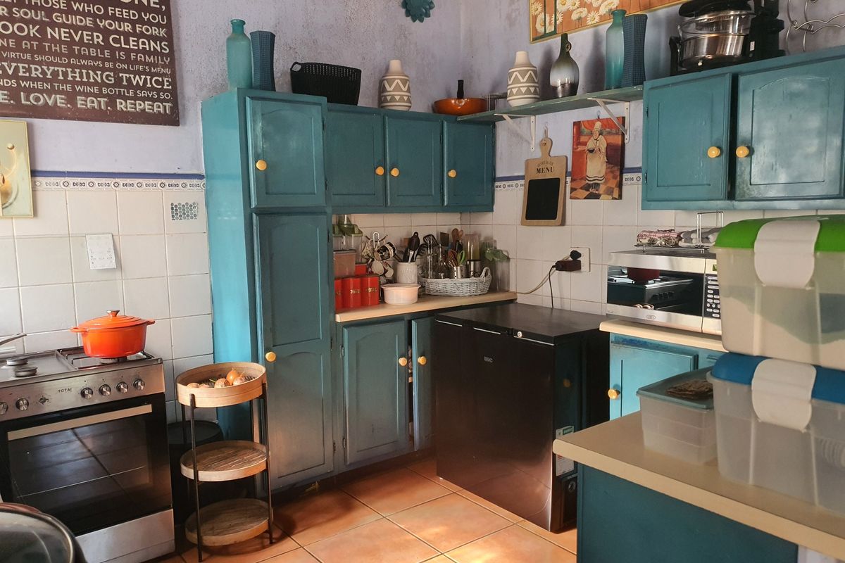 A functional kitchen featuring teal-painted cabinetry, tiled backsplash, and tiled flooring, equipped with a freestanding oven and built-in microwave.