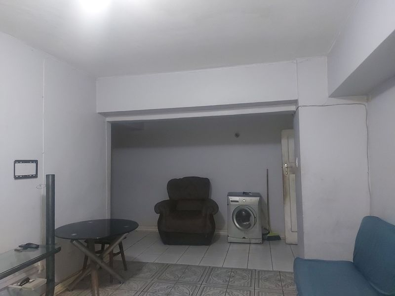 Open plan living area featuring tiled flooring and a structural ceiling bulkhead, offering a functional layout for versatile use.