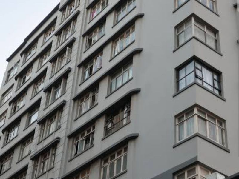 A multi-story apartment building facade featuring a grey painted exterior and numerous casement windows.