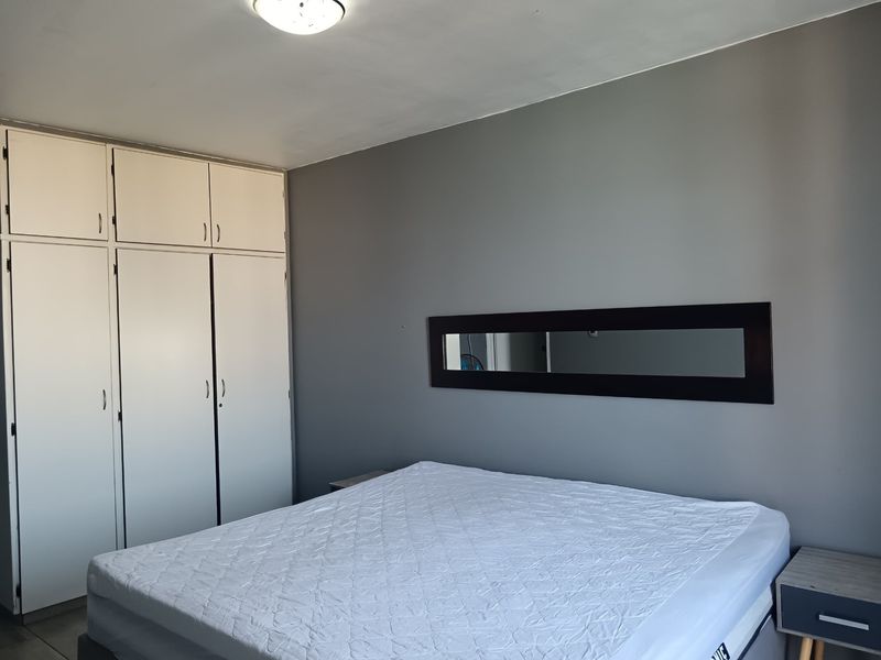 A bedroom featuring grey walls and white built-in cupboards providing ample storage space.