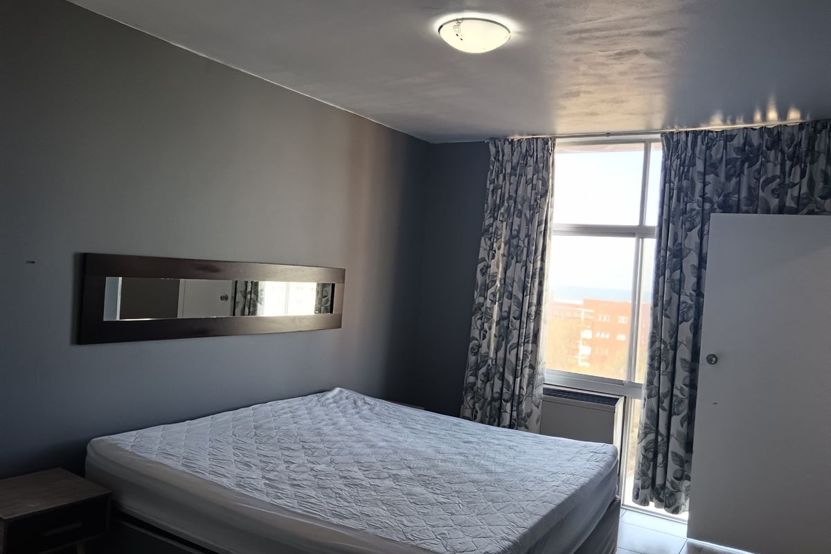 A bedroom featuring dark grey walls, a large window with natural light, and a ceiling light fixture.