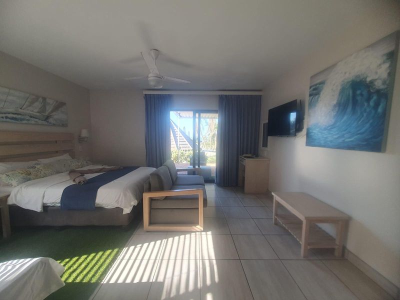 Spacious bedroom featuring tiled flooring, a ceiling fan, and direct access to an outdoor patio through sliding glass doors.