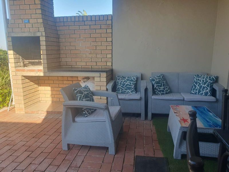 A covered outdoor patio area featuring a built-in brick braai and brick paved flooring, ideal for outdoor entertaining.