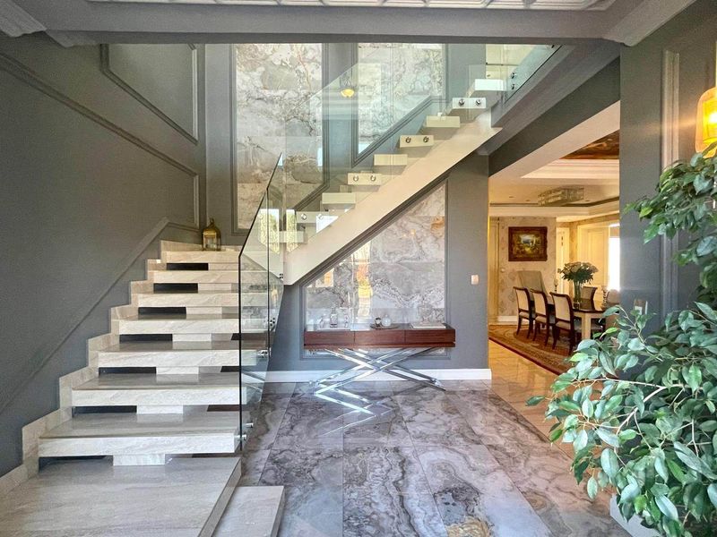 Grand entrance foyer featuring a striking marble staircase with glass balustrade, premium marble flooring, and elegant wall paneling details.
