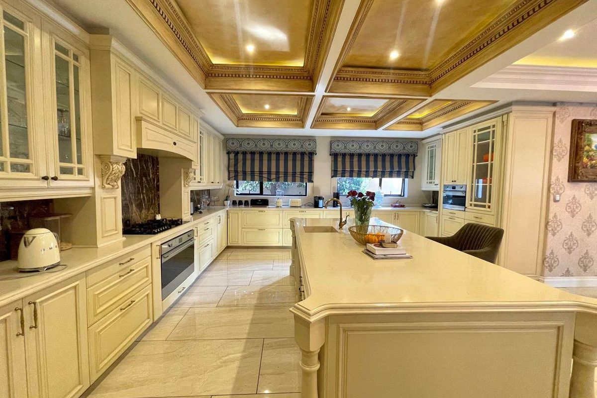 Spacious traditional kitchen featuring a large central island, stone countertops, custom cabinetry, and an elegant coffered ceiling with integrated lighting.