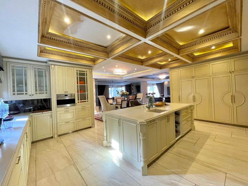 Spacious open-plan kitchen and dining area featuring a large central island, custom cabinetry, and an elegant coffered ceiling with integrated lighting.