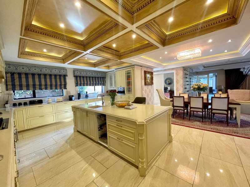 Spacious open-plan kitchen and dining area featuring a large central island, custom cabinetry, and an elegant coffered ceiling with integrated lighting.