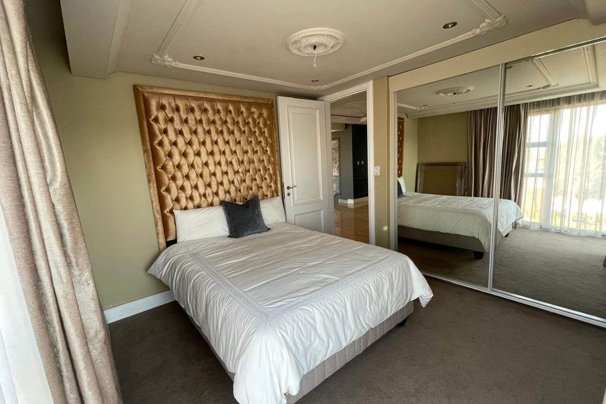 A well-maintained bedroom featuring a built-in mirrored wardrobe, decorative ceiling rose, and coving, providing a classic and functional living space.