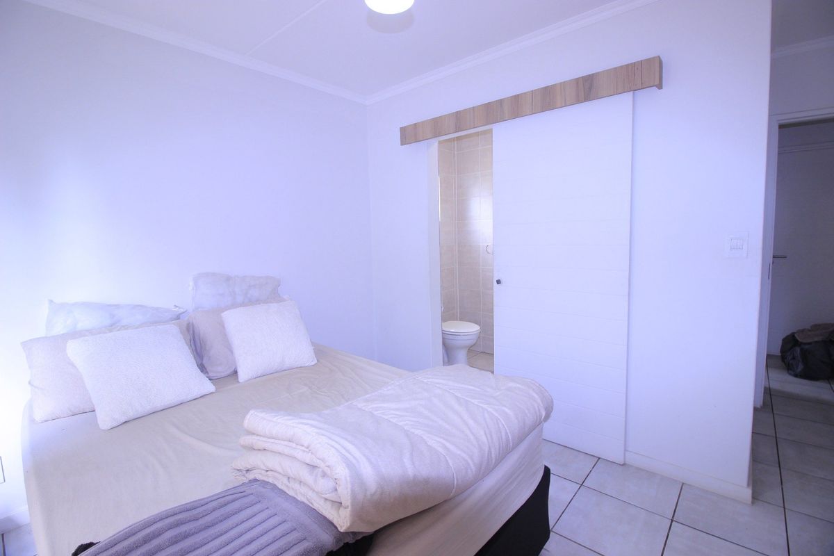 A bedroom featuring tiled flooring and a modern sliding barn door providing direct access to an en-suite bathroom.