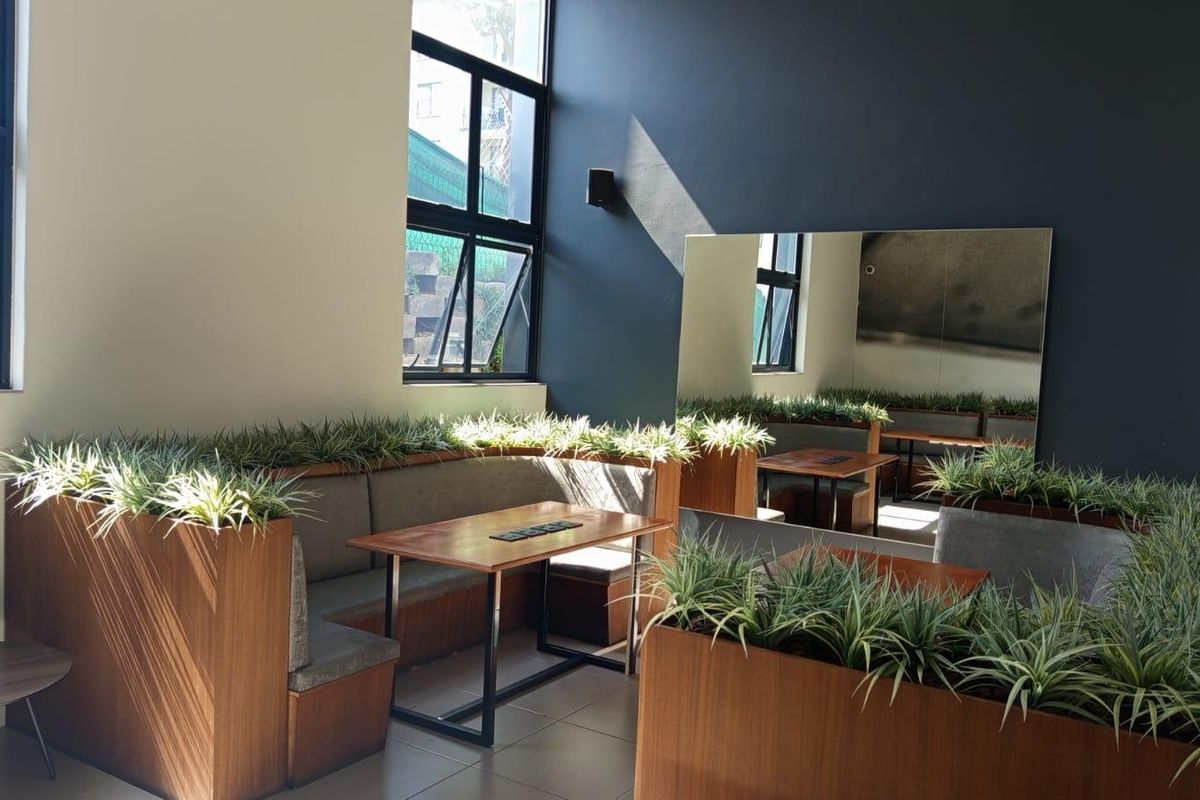 A modern living area featuring built-in bench seating, large wall mirror, and tiled flooring with natural light from tall casement windows.