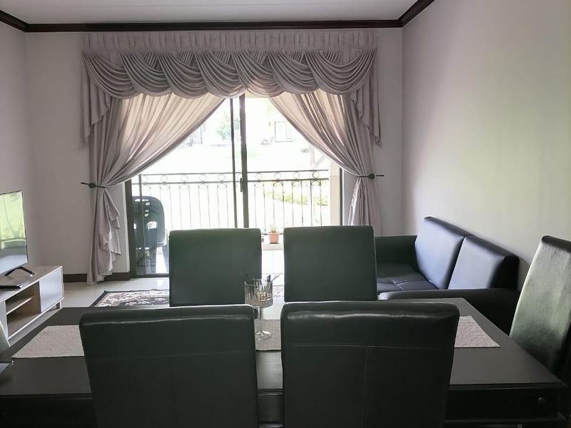 Open plan living and dining area featuring tiled flooring, crown molding, and a sliding glass door leading to a balcony.