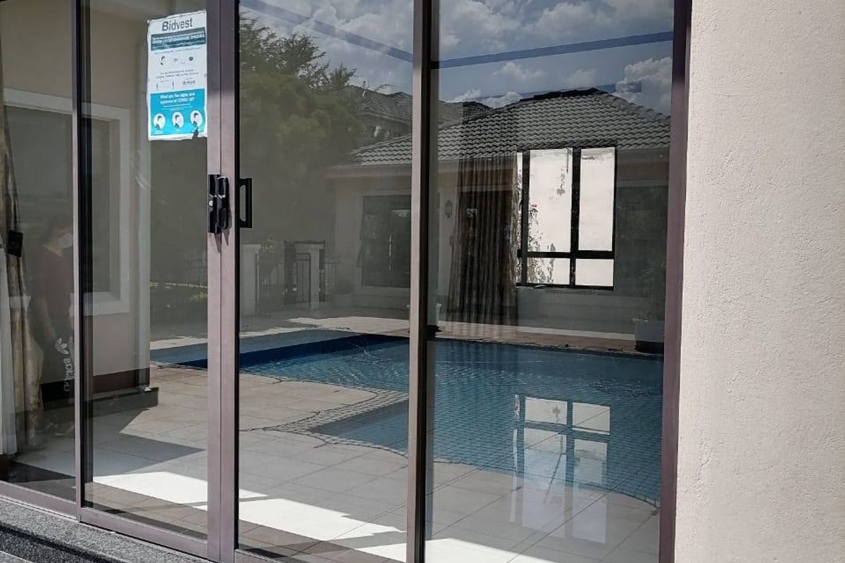 Rear exterior view featuring large sliding glass doors leading to a patio area with granite steps and a swimming pool visible in the reflection.
